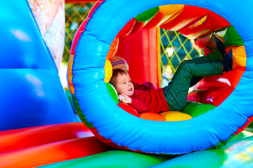 Wall Mural - cute happy kid, boy playing in inflatable attraction on playground