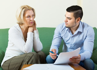 Elderly woman and young man with bills.