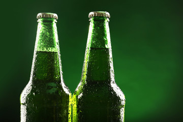 Poster - Glass bottles of beer on dark green background