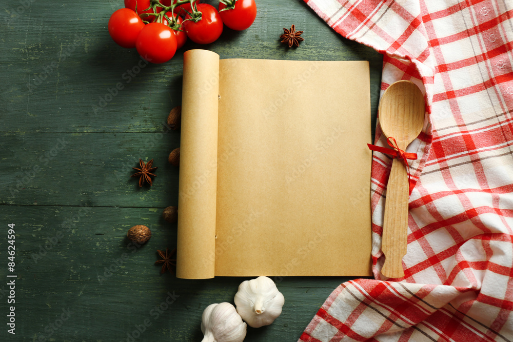 Open recipe book, vegetables and spices on wooden background