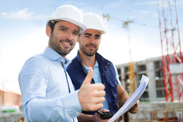 Wall Mural - Engineer and worker watching blueprint on construction site