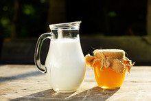 A Jug Of Milk And Honey On Wooden Table