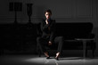 fashionable woman in black suit in dark minimalistic interior