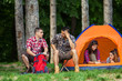 © bokan - Two young men talking and searching for something in backpack while sitting in front of the tent. Two young women relaxing and talking in a tent