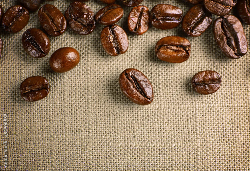 Frame of coffee beans on color sackcloth background