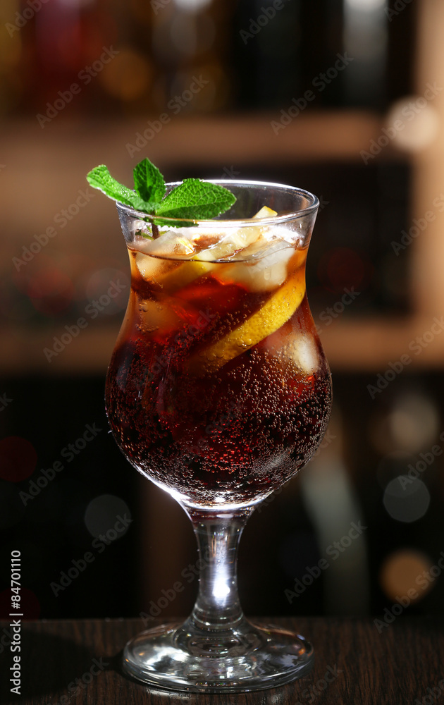 Glass of cocktail in bar on bright blurred background
