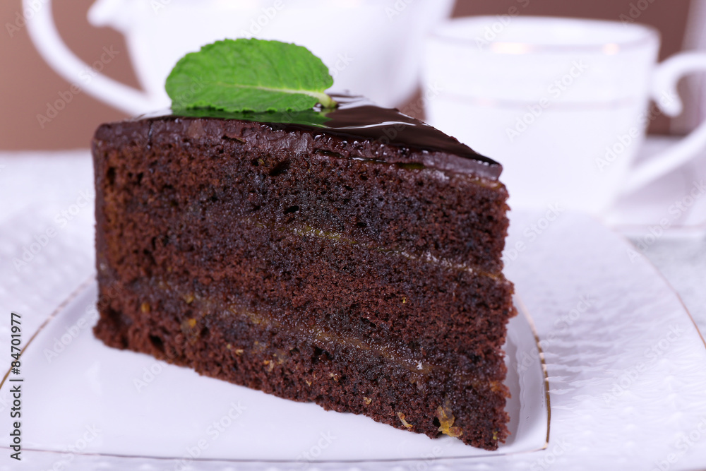 Piece of chocolate cake with mint on white plate, closeup