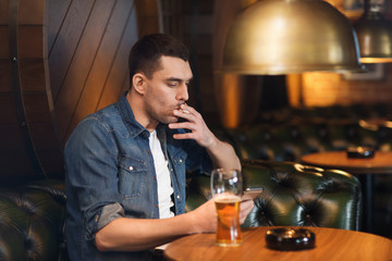 man drinking beer and smoking cigarette at bar