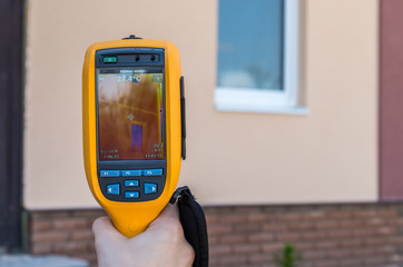 Man inspect house window with thermal imaging camera