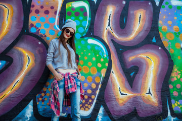 Wall Mural - beautiful cool girl in hat and sunglasses over graffiti wall