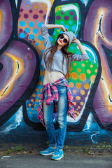 Wall Mural - beautiful cool girl in hat and sunglasses over graffiti wall