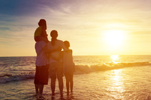 Happy Family Watching The Sunset On The Beach