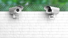 Security Surveillance Camera On White Brick Wall With Chain-link Fence