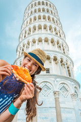 Woman biting slice of pizza by Leaning Tower of Pisa