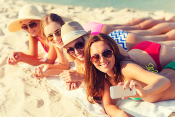 Sticker - group of smiling women with smartphone on beach