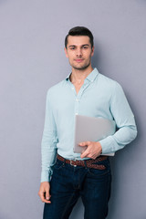 Poster - Handsome man standing and holding laptop