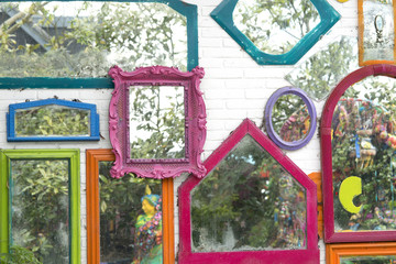 mirrors with colored frames on white stone wall