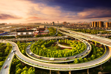 Elevated overpass with skyline of modern city during sunset.