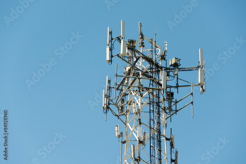 Fotografie, Tablou Cell phone communication tower with multiple antennas against a blue sky