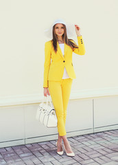 Wall Mural - Beautiful young woman in yellow suit clothes and hat with handba