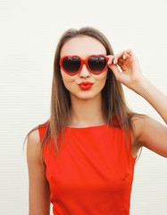 Wall Mural - Portrait of pretty woman in the red sunglasses blowing lips havi