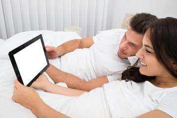 Wall Mural - Couple On Bed Looking At Digital Tablet