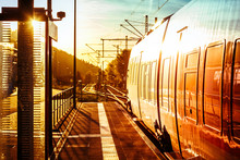 Modern Passenger Train Standing At Countryside Platform With Beautiful Landscape At Sunset.