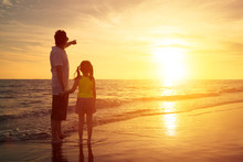 Father And Daughter Standing On The Beach Watching Sunset