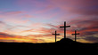 three crosses in silhouette on a hill with sunset