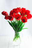 Fototapeta Tulipany - Red tulips glass gar on wood table