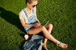 © WHstudio Leushin N - Young blonde girl using tablet outdoor sitting on grass and smil