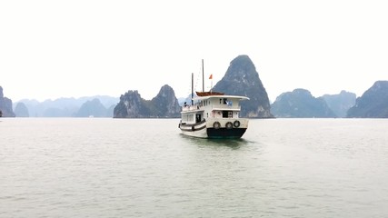 Wall Mural - Tourist travel cruise boat in Ha Long Bay in Vietnam. Halong also known as Descending Dragon Bay is famous landmark of Vietnam. HD footage video of beautiful sea and limestone island mountains