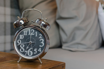 classic style alarm clock on wooden table in bedroom