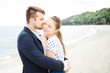 © ilya_oreshkov - European couple relaxing on the sea beach hugging each other and talking