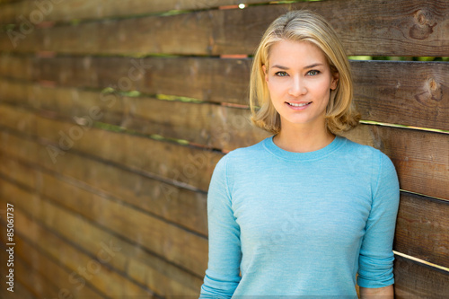 Fotografie, Tablou Beautiful blonde woman portrait smiles next to wood fence
