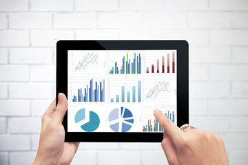 Poster - Close up hand holding digital tablet with analyzing graph agains