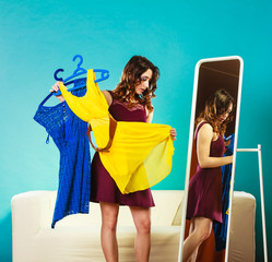 woman shopper holds hangers with clothes looking in mirror