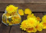 Fototapeta Dmuchawce - Flower honey in a glass jar and dandelions on a wooden table