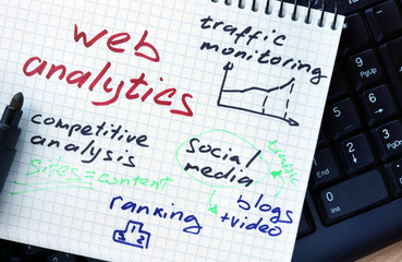 Notepad with words web analytics  on a wooden background