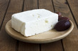 Greek feta cheese with kalamata olives on rustic plate and table