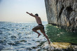 © theartofphoto - Young shirtless athletic man jumping in water by ocean shore
