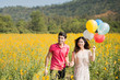 © torwaiphoto - Couple playing in the garden flowers yellow balloons.