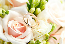 Gold Wedding Rings On A Bouquet Of Flowers For The Bride