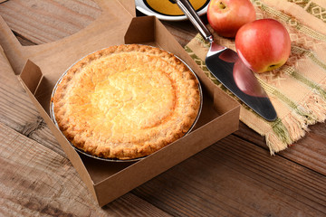 Closeup of a fresh apple pie in a bakery box on a rustic wood table. 