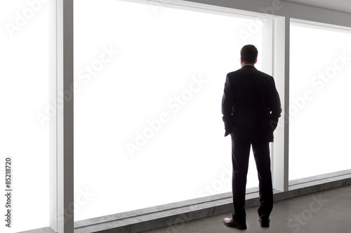 Fényképezés  Middle aged businessman looking out a bright office window and thinking