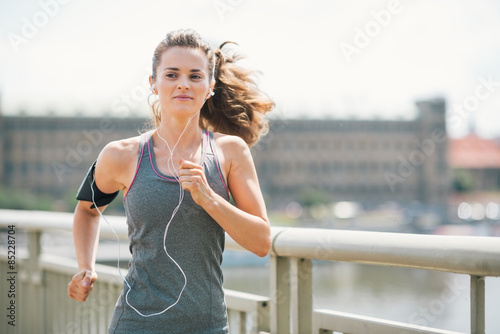 Foto Lächelnde Frau Joggen in der städtischen Einstellung Musik hören