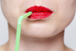 © grufnar - close up of a woman's lips with red lipstick and green straw