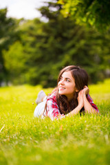 Wall Mural - Beautiful woman lying on green grass