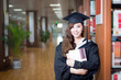 © zhu difeng - asian female student holding book and wearing academic dress in