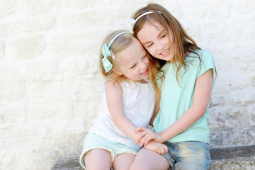 two adorable little sisters laughing and hugging